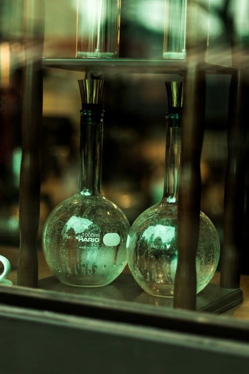 Volumetric flasks on a shelf in green-tinged laboratory light